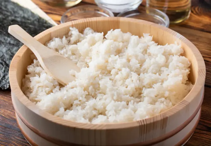 Gotowany ryż do sushi w drewnianej kadzi z drewnianą łopatką.