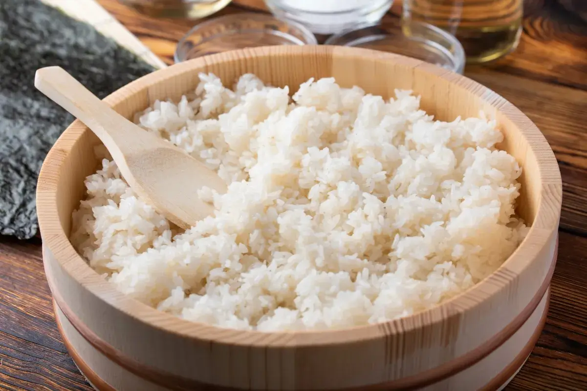 Gotowany ryż do sushi w drewnianej kadzi z drewnianą łopatką.